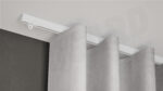 Weiße 1-läufige Aufputz-Gardinenschiene Modell 410 mit fließendem Vorhang, verdeckt montiert an weißer Decke.