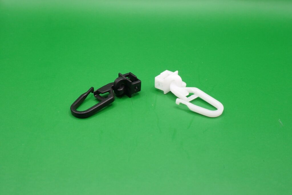 Zwei Gardinengleiter Clic 6 mm mit langem Haken in Schwarz und Weiß, nebeneinander liegend