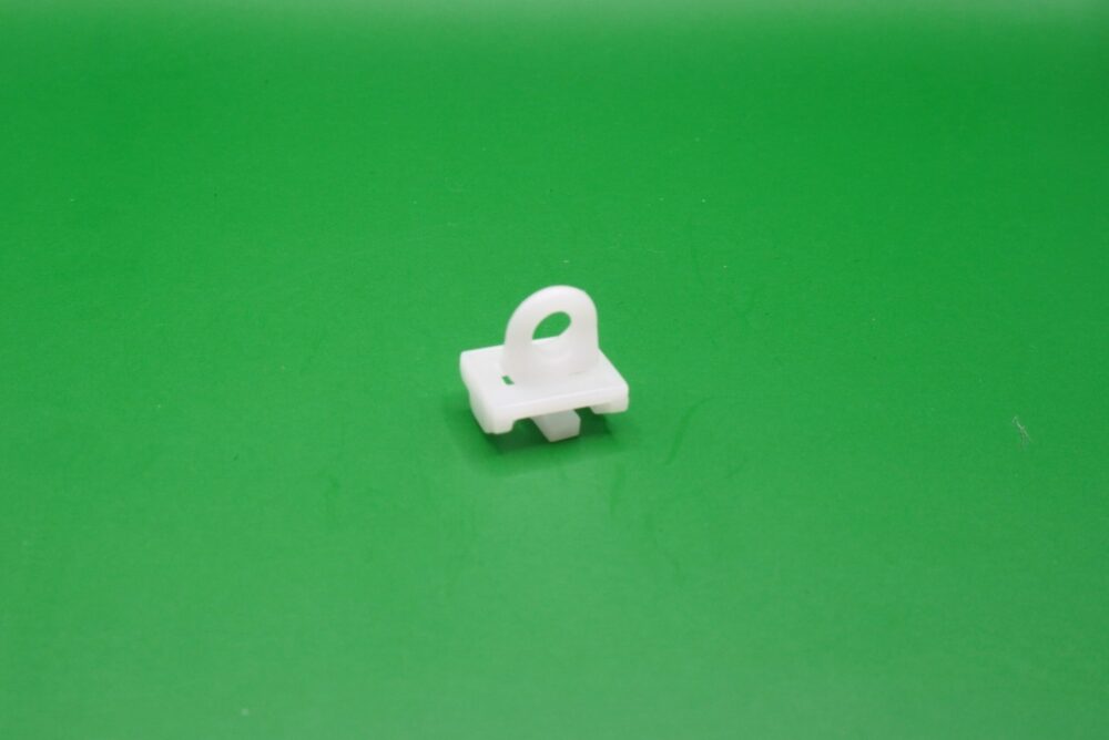 Weißer Zwischenfeststeller für Gardinenschienen mit 6 mm Lauf auf grünem Hintergrund.